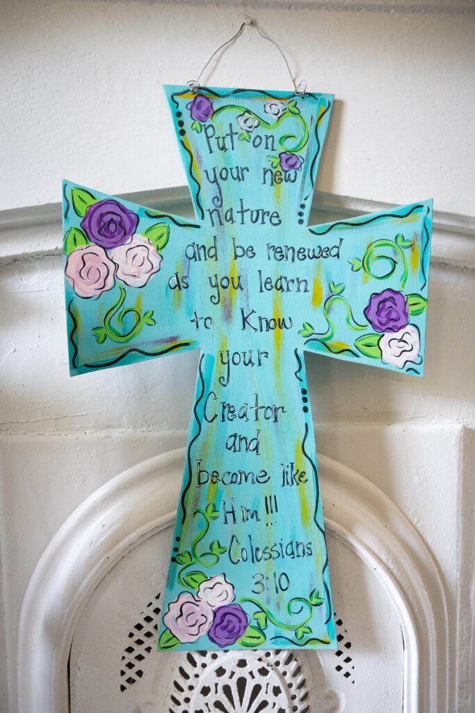 A hand-painted cross at a Warriors Center campus inscribed with Colossians 3:10